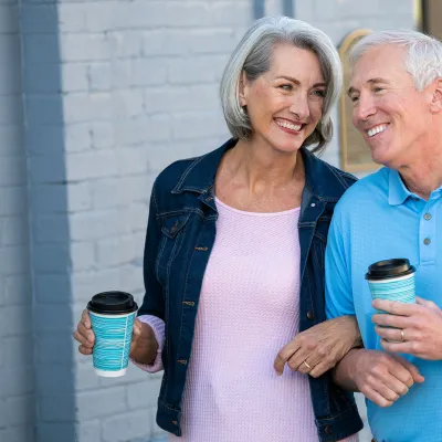 Older couple walking with coffee