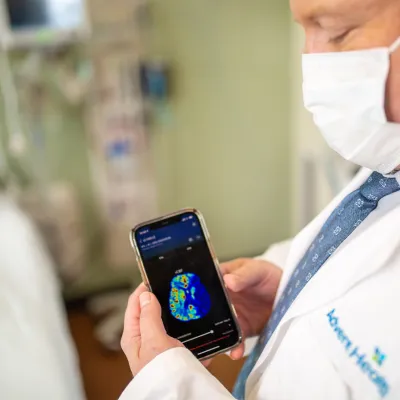 Physician holding a smartphone with a brain scan on screen.
