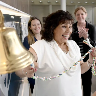 A happy woman ringing the bell at Winter Park Cancer Center.