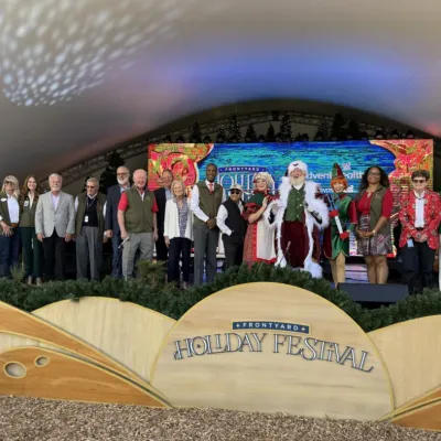 Elected officials, community partners, Mr. and Mrs. Claus, and a festive elf gather for the ribbon-cutting ceremony, officially ushering in the start of the Frontyard Holiday Festival.