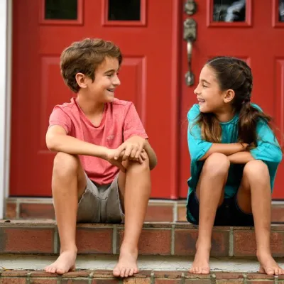 A boy and girl make jokes while sitting on their porch