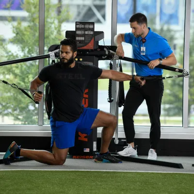 A man works with his personal trainer to do a chest fly exercise.