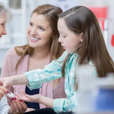 A little girl with diabetes tests her blood sugar at the doctor.