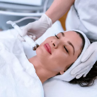 A woman lying on her back with her eyes closed, receiving laser treatment.