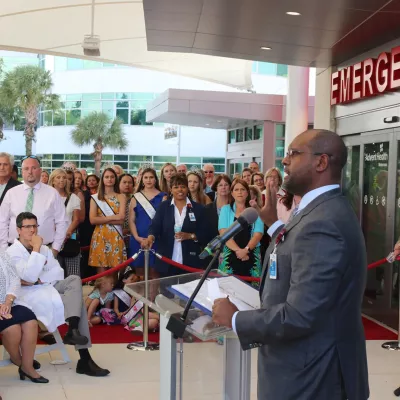 A crowd of people listening to the grand opening speech from an AdventHealth employee