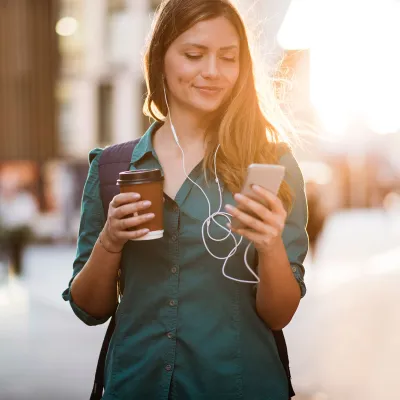 Woman drinking coffee in the morning while looking at her phone.