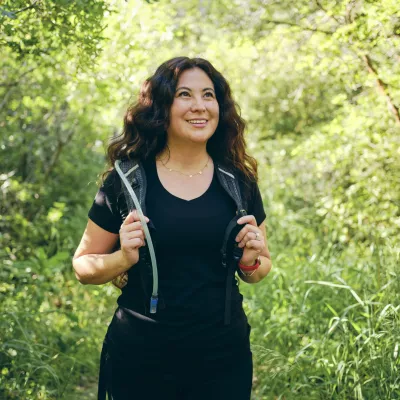 A woman on a hike while wearing a Camelbak backpack.