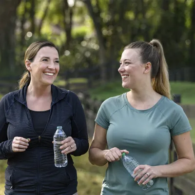 Two women holding water bottles walking together outside 