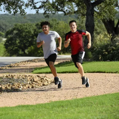 Two young men running outside on a path.