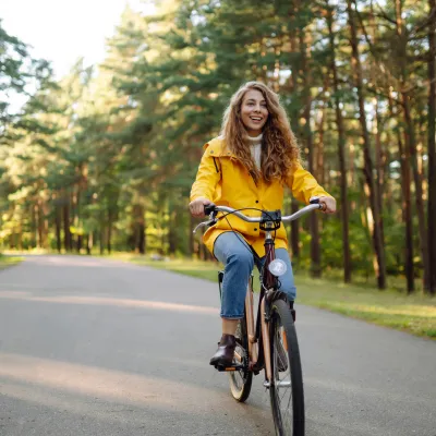 Woman riding on a bicycle in a forested area.
