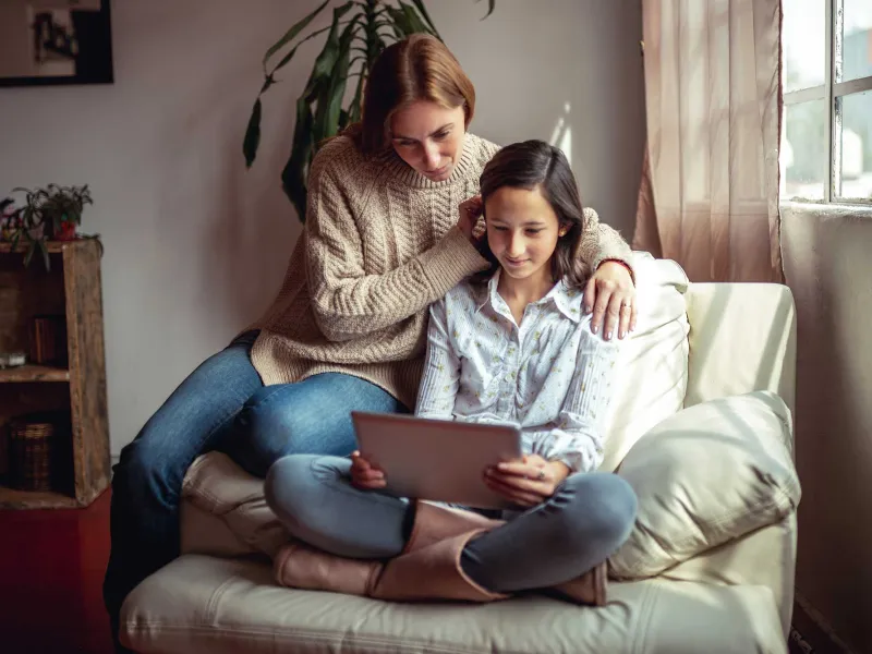 A mother and daughter reading from a tablet