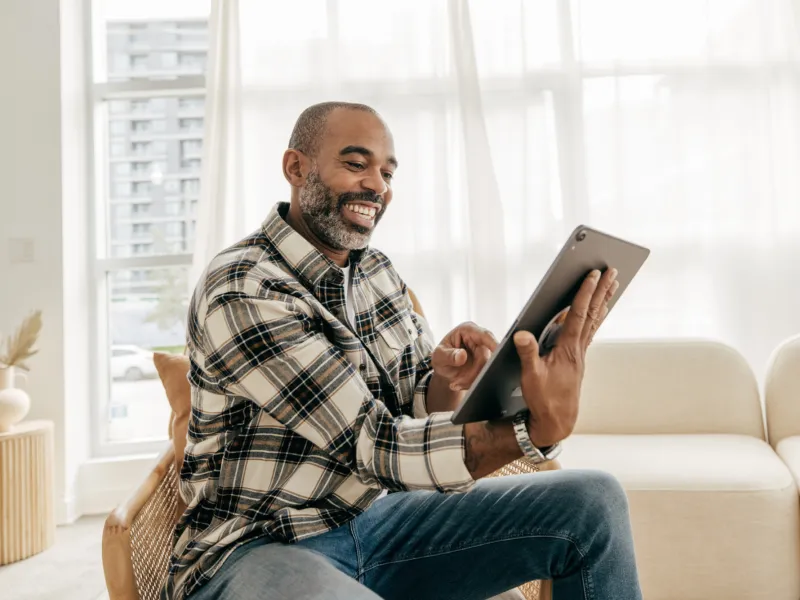 A Man Smiles During a Video Call on His Tablet in His Home.
