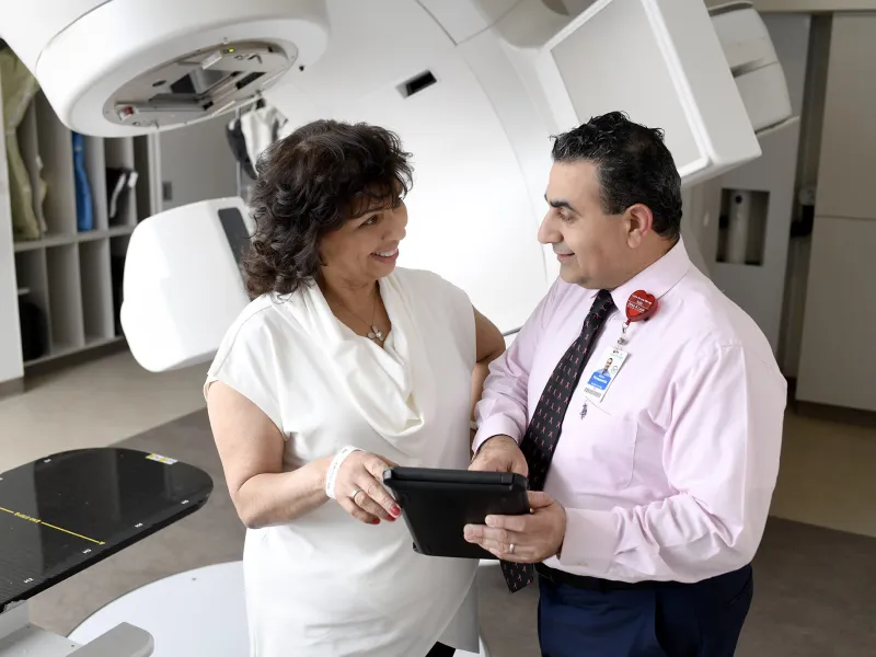 A physician reviewing medical data on a tablet with his patient.