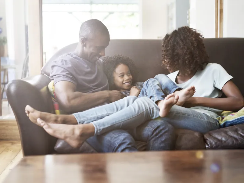 An African American family hangs out on the couch at home.