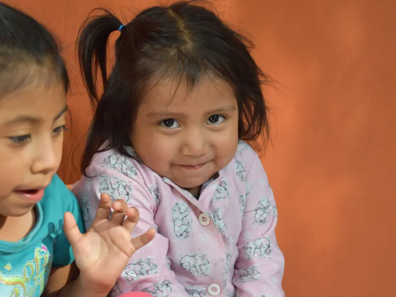 A Guatemalan girl tries stifle a smile when looking into the camera.