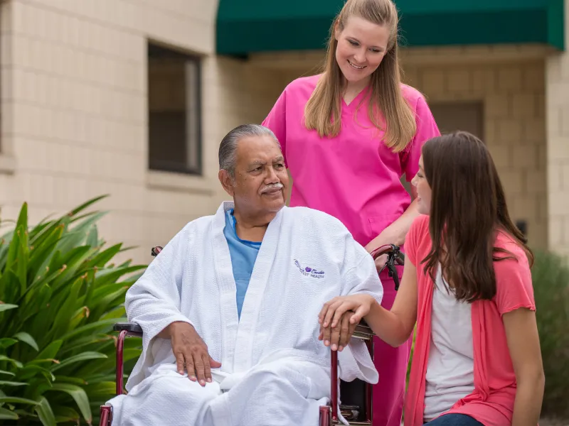 Elderly man in a wheelchair with his daughter and a hospice nurse.