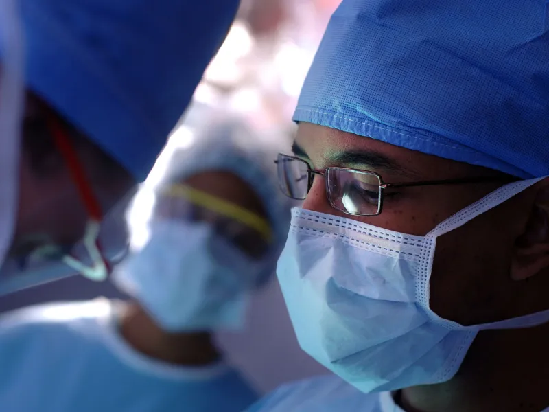 Male surgeon wearing glasses and a face mask.