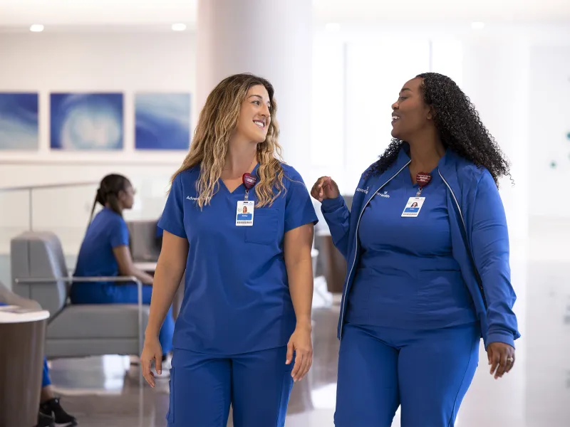 Two nurses walking together having a conversation.