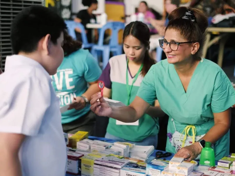 A nurse assisting a young boy from the Philippines