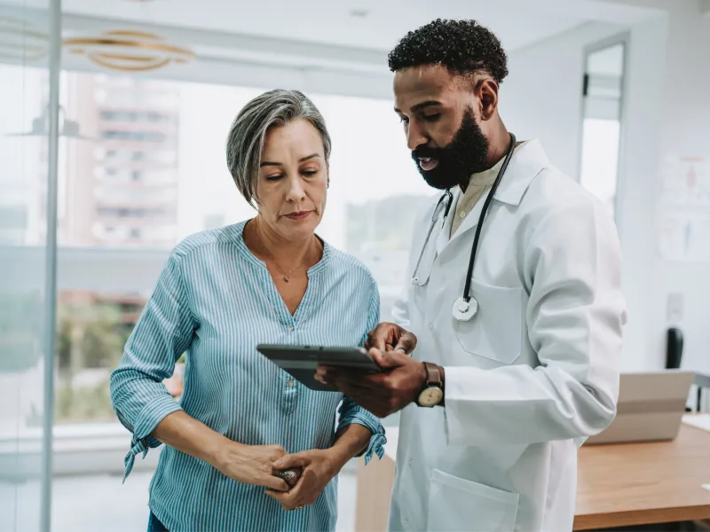 An older woman reviews test results on a tablet with her physician.