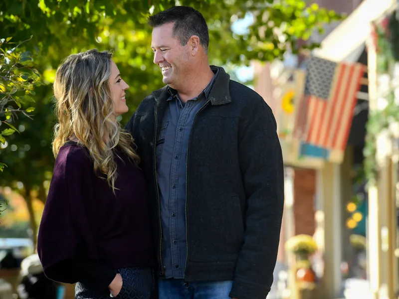 Couple embracing on a sidewalk outside.