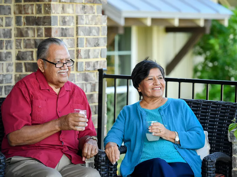 Couple sitting on the porch drinking lemonade.