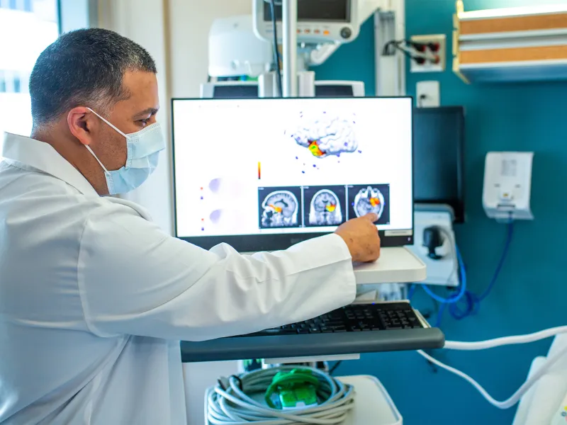 Physician pointing at a brain scan on a screen.