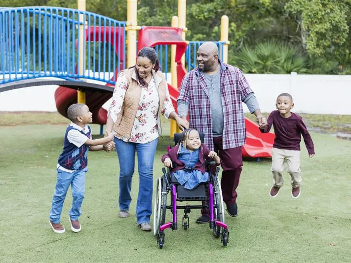 A family with 3 children, one in a wheelchair, at the park.