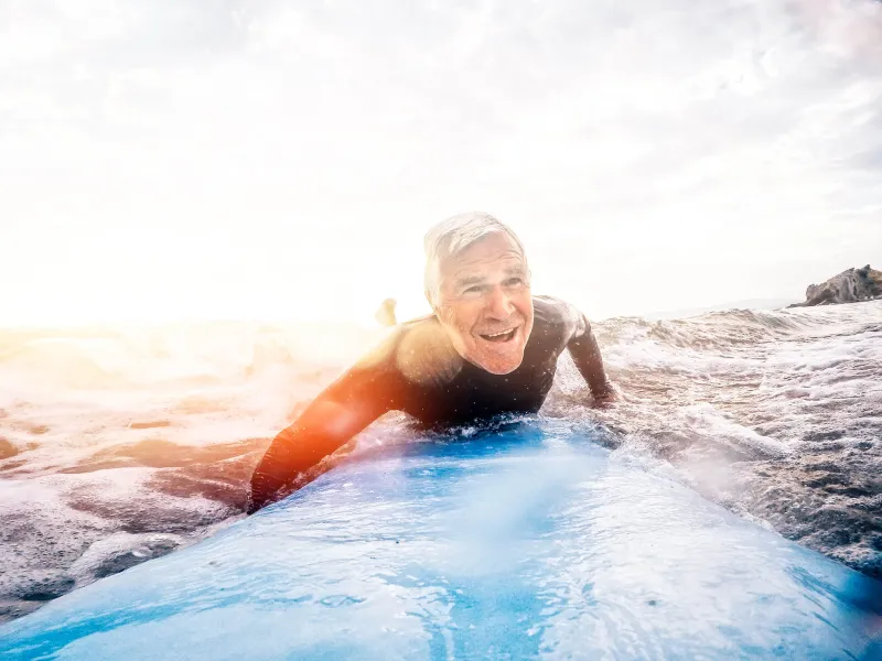A Surfing Senior Smiles as he Paddles in the Ocean