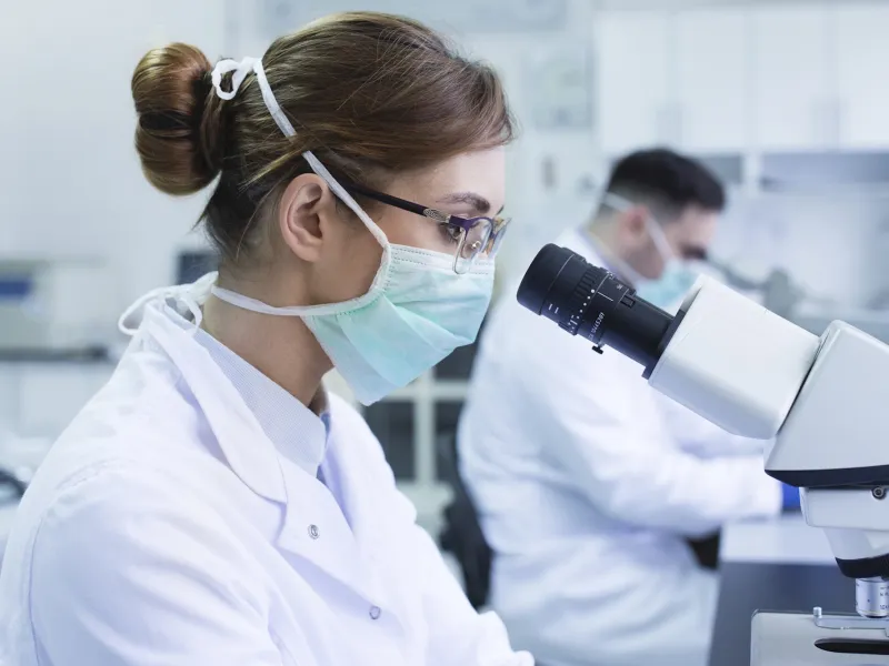 A woman looking through a microscope in a lab.