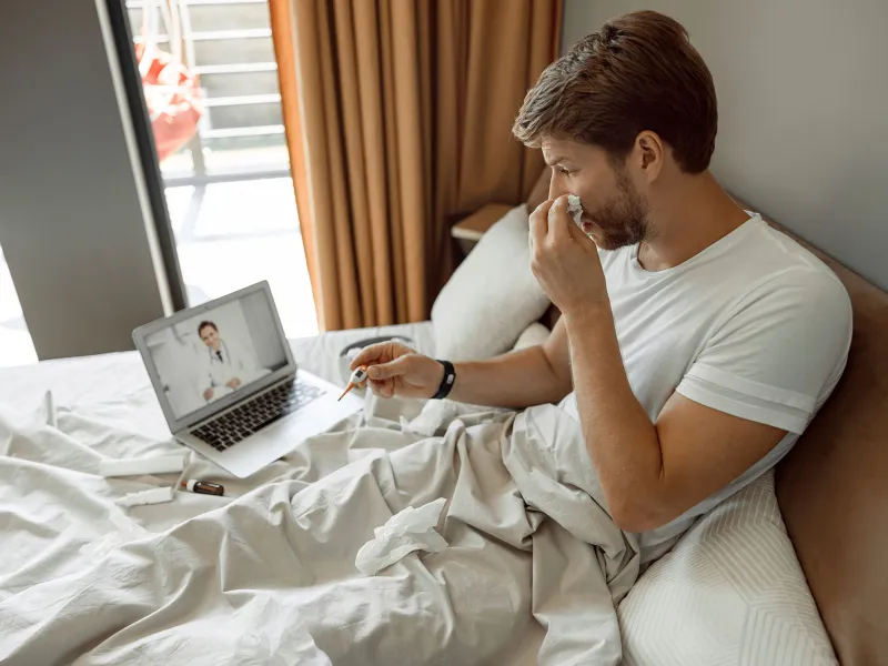 A young man has a remote check up with his doctor from home