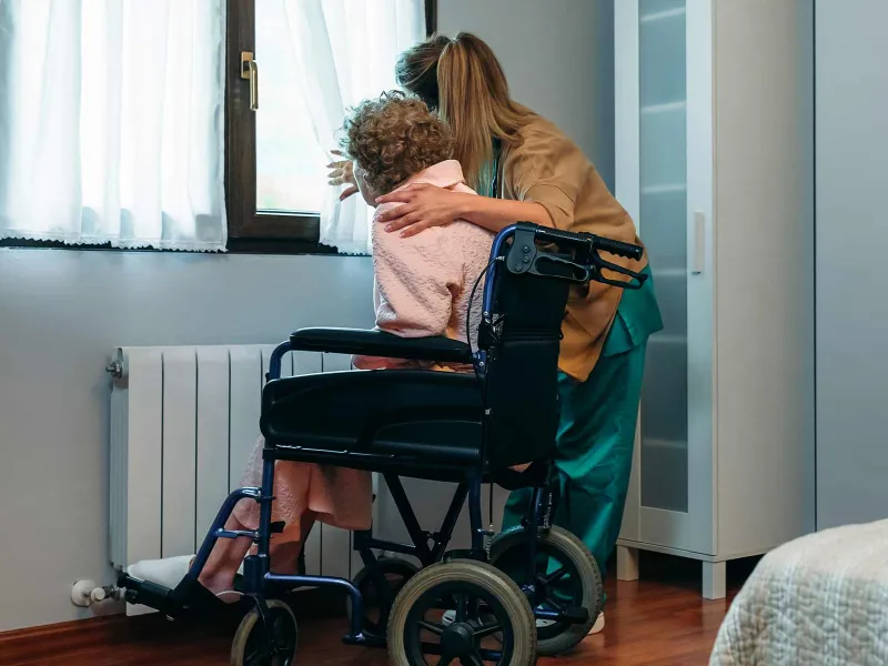 Woman embracing elderly woman in hospice