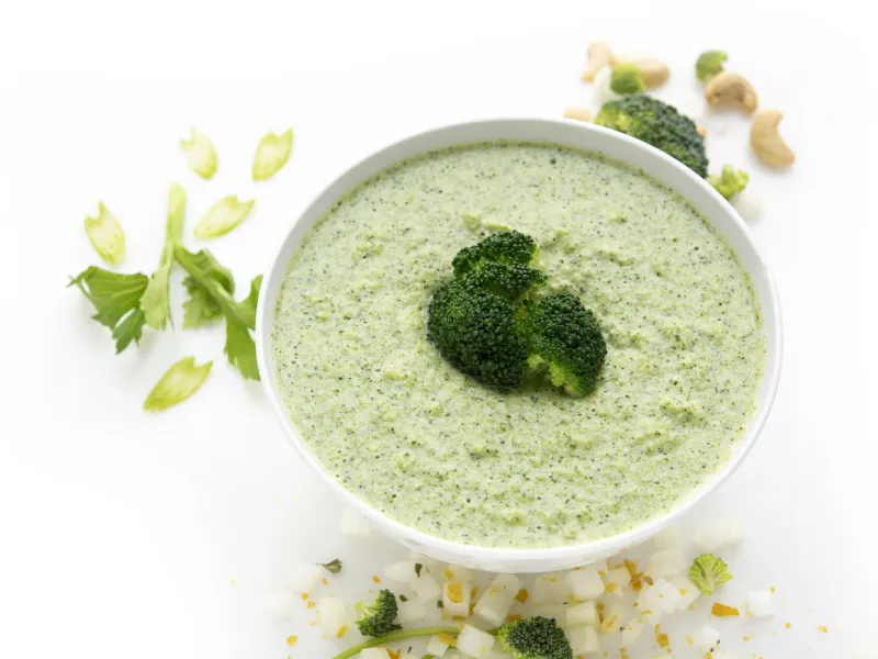 Bowl of broccoli cream soup with onion and parsley garnish