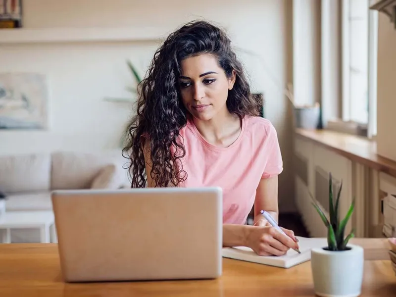 Young woman at table with laptop and notebook