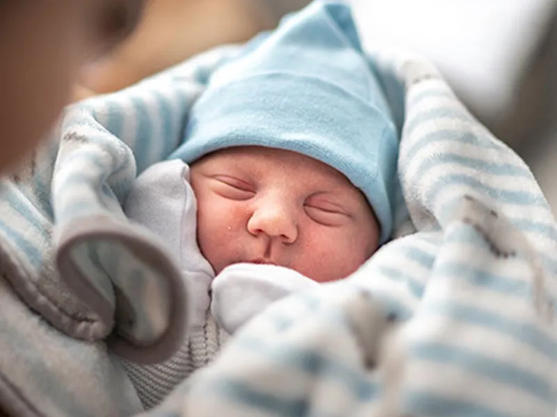 a-newborn wrapped in a striped blanket sleeps peacefully