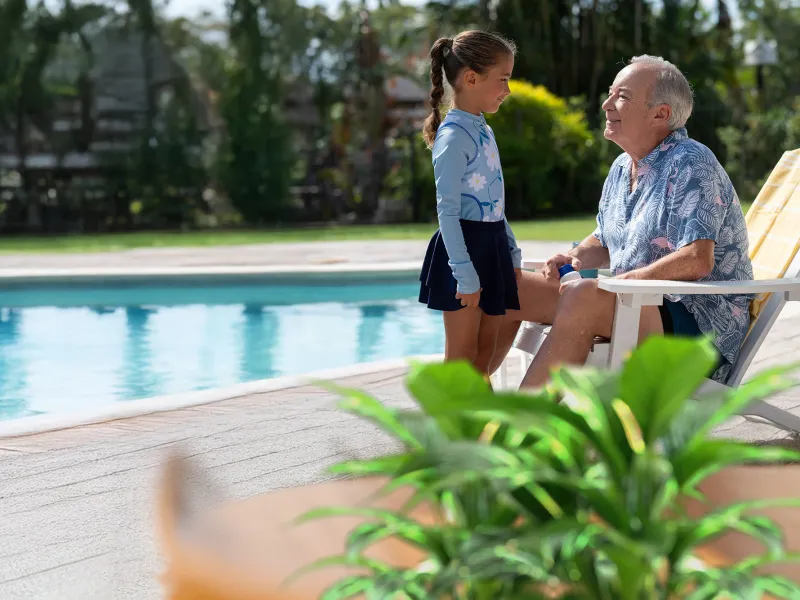 grandpa and granddaughter smiling near pool