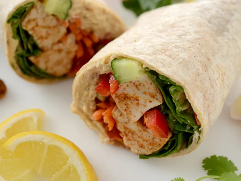Two halves of chicken veggie wrap with lemon garnish