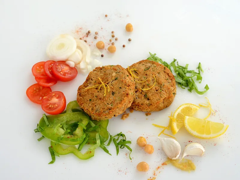 two falafel patties in the center of veggies and seasonings