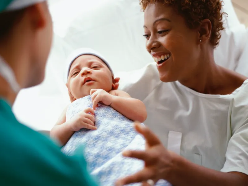 Nurse presents newborn baby to mother.