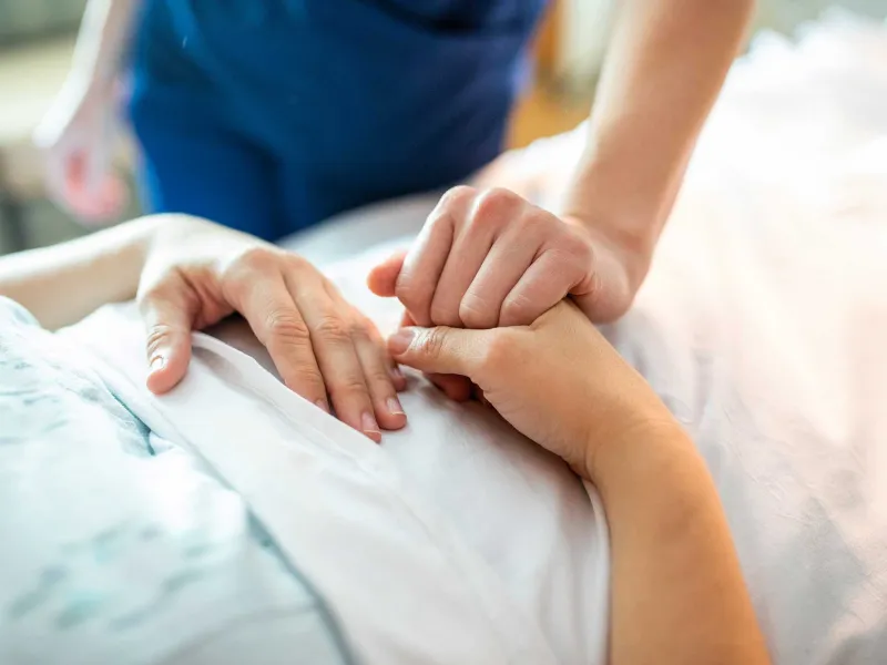 A nurse holding a patient's hand to comfort.