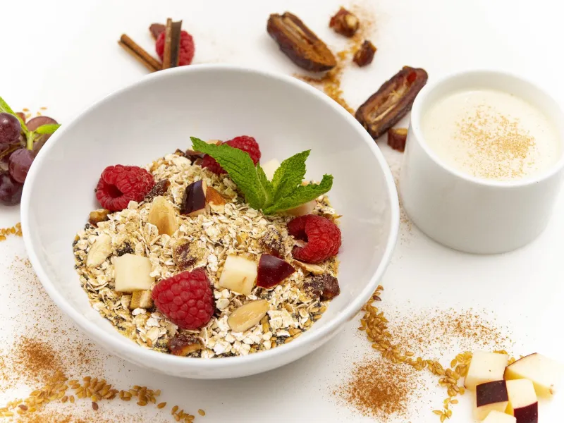a bowl of oats, topped with fresh raspberries and chunks of apple