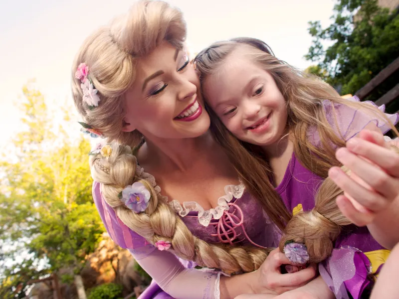 Disney Rapunzel character in the park with a young girl.