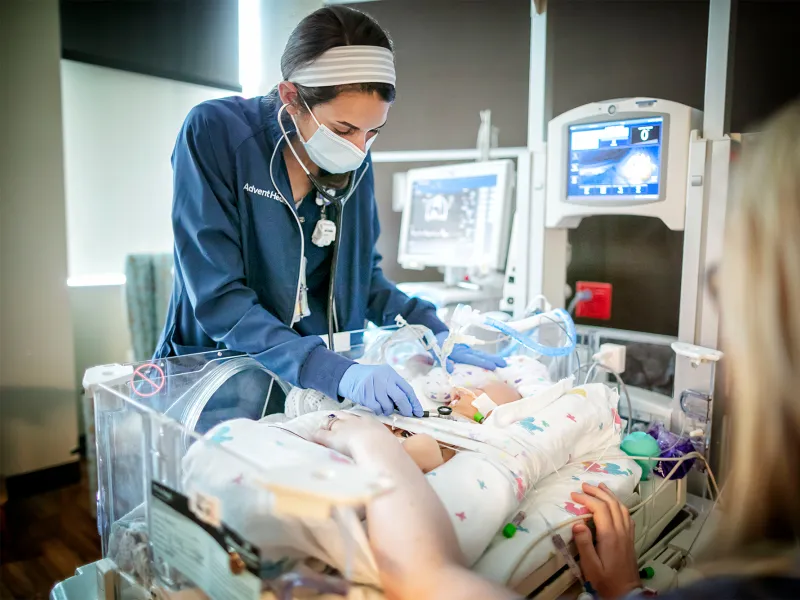 Nurse examining a newborn in the NICU.