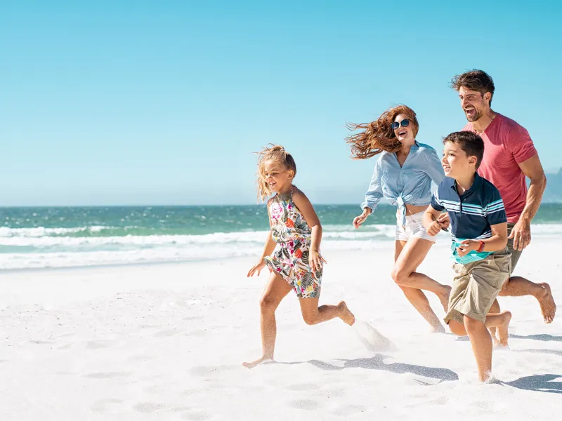 A happy family running together on the beach.