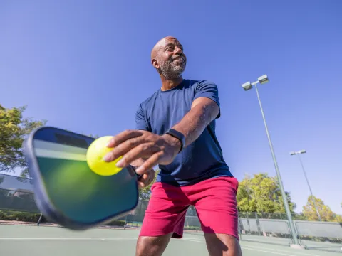 A man playing pickleball outdoors.