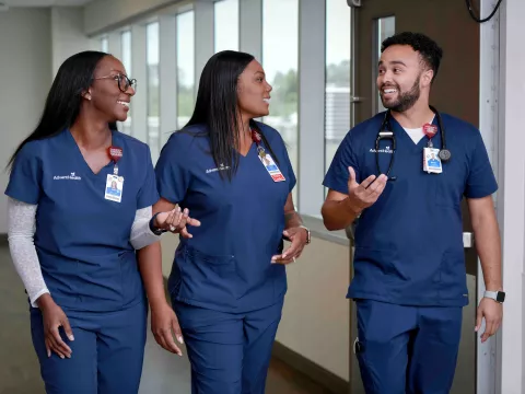 Three AdventHealth nurses talking while waking down a hall