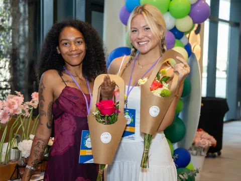Women attending the Women’s Health and Cancer Prevention Event, holding two bouquets of flowers.