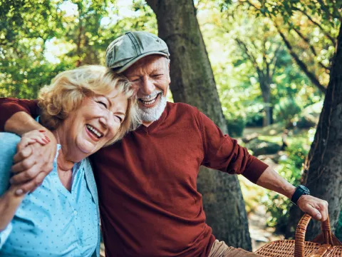 Man and woman laughing together in a forest.