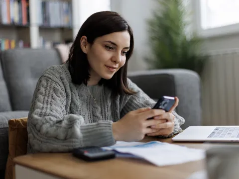 A woman checks her phone while sitting at a table.