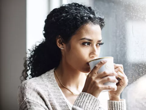 Woman drinking coffee by the window.